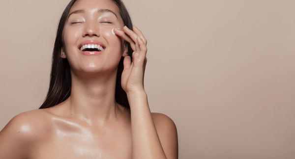 Happy woman applying skin care to her face.